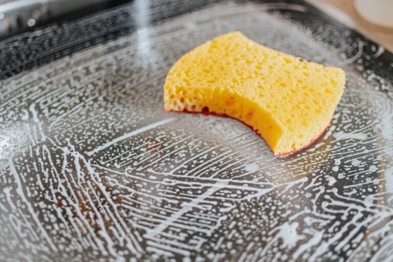 Yellow sponge cleaning a soapy glass surface, highlighting retail store cleanliness for enhanced appeal.